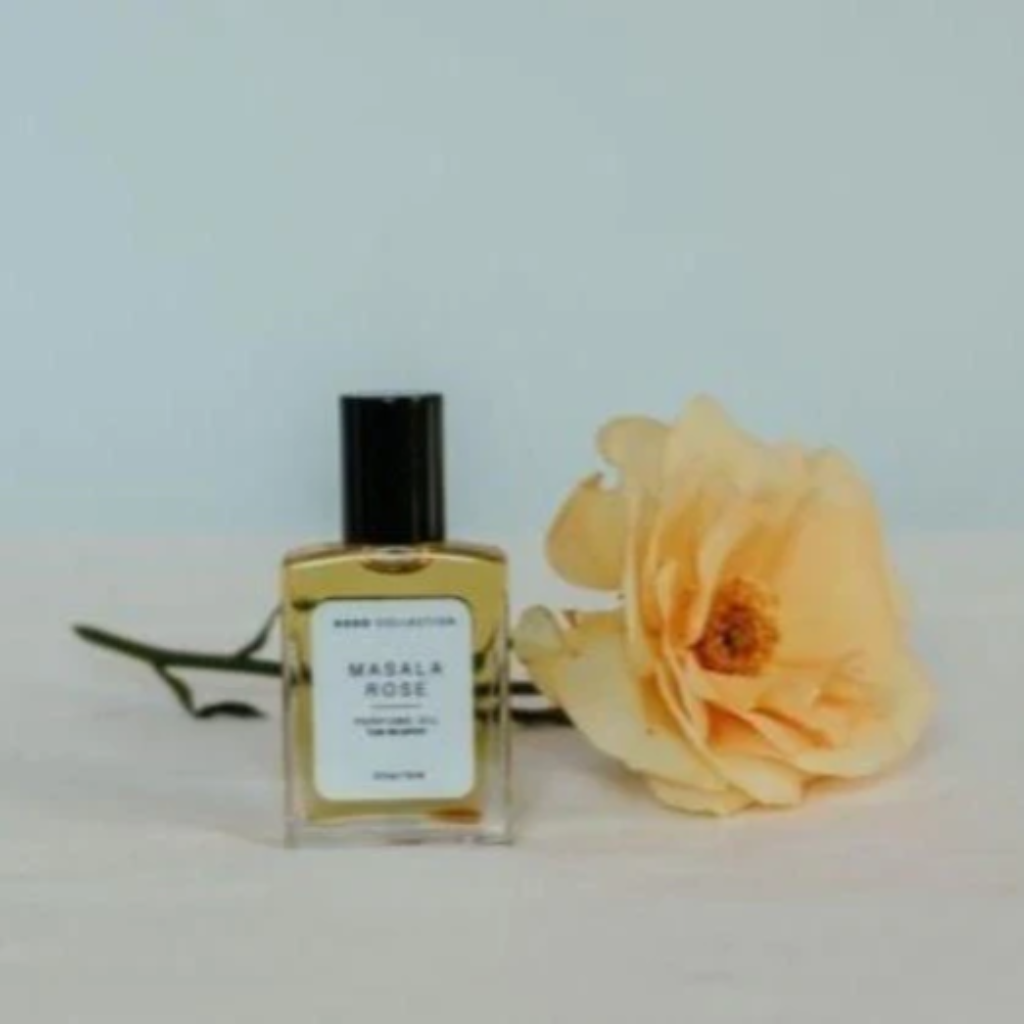 Perfume Oil |  Elizabeth Homestead (bottle of masala rose perfume oil siting on a table in front of a peach coloured rose)